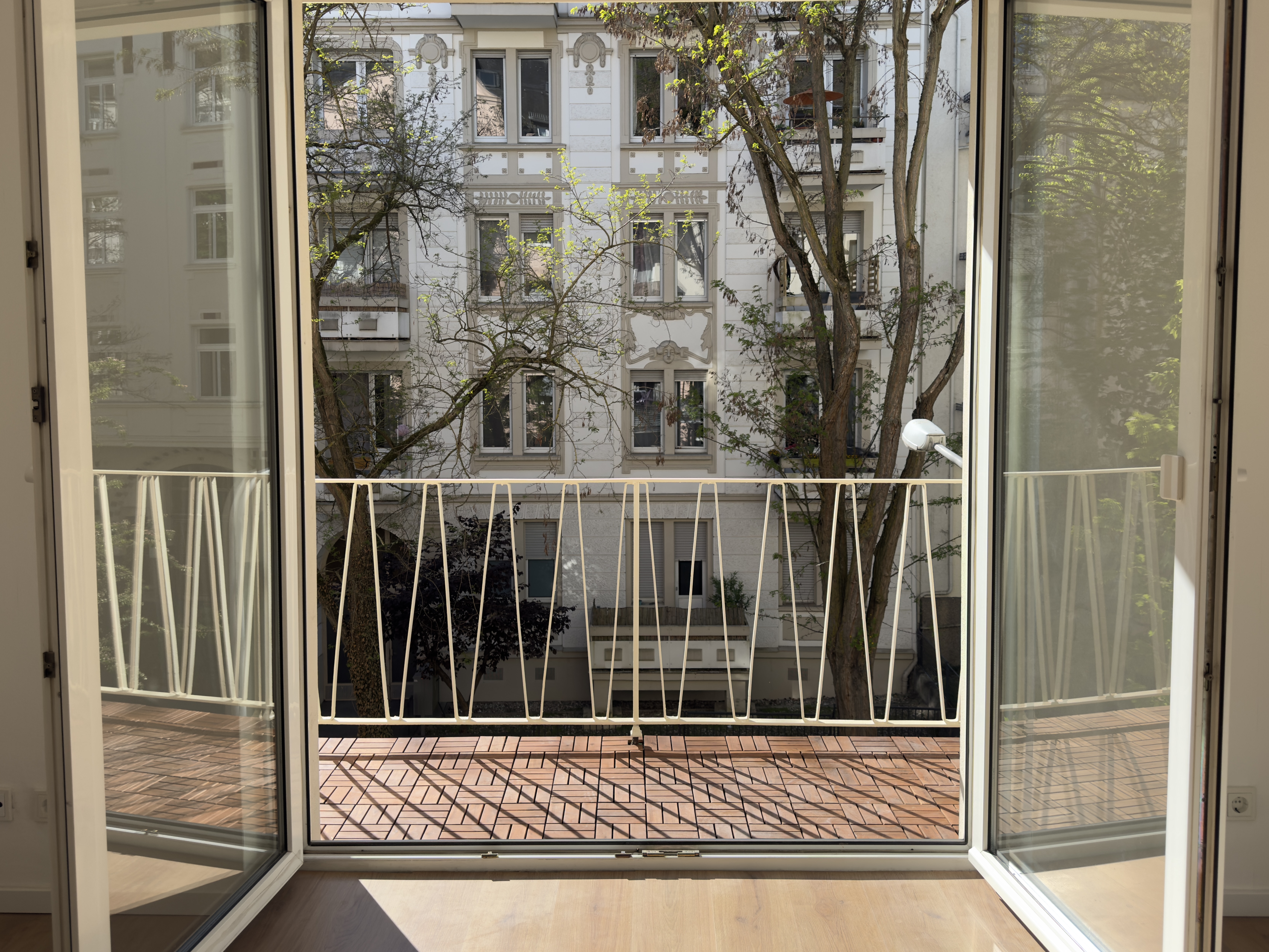 Blick durch die Balkontür auf Altbaufassade
