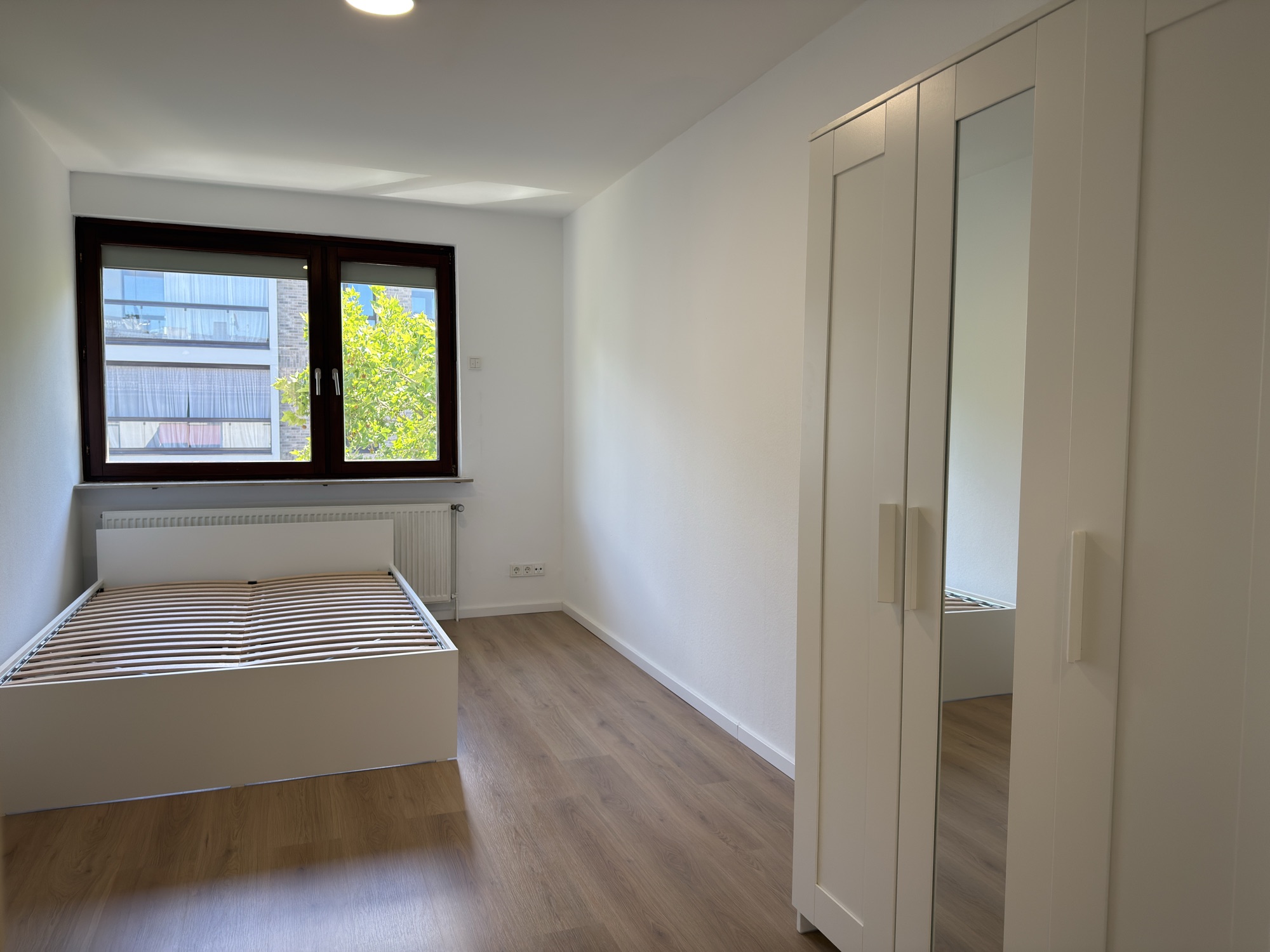 Zimmer mit Kleiderschrank und Fenster ins Grüne